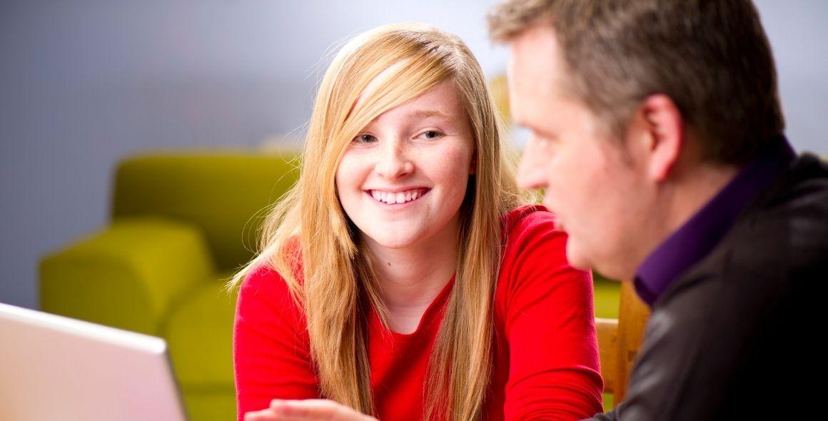 tutor talking to student in front of laptop computer